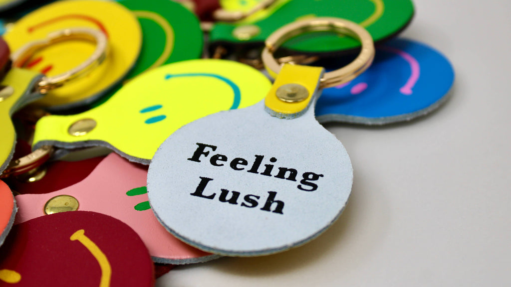 Colorful keychains with a keychain labeled 'Feeling Lush' on a light background